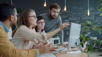 Équipe collaborant autour d'un écran pour élaborer une stratégie sur mesure